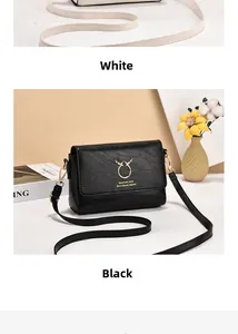 Close-up detail of white and black crossbody bags with golden deer logo and leather texture