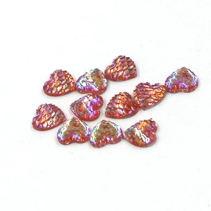 Macro shot of heart-shaped resin charms with orange fish scale texture and iridescent glow