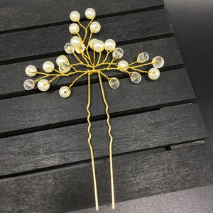 Close-up of golden wire bridal hair pin with white pearls and clear crystal beads