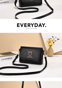 Close-up of black textured leather crossbody bag with golden deer head metal clasp