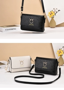Detailed view of luxury leather crossbody bag featuring gold stag logo and brand text