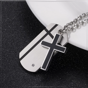 Detailed view of titanium steel cross pendant and black rectangle tag with small crystal