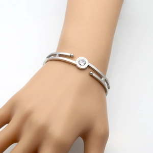 Silver Roman numeral hollow bangle with clear center zircon shown on wrist