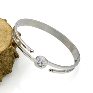 Macro view of silver Roman numeral bangle with a central sparkling gemstone on a wooden stand