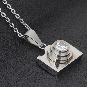 Close-up of vintage camera necklace pendant with shiny stone and silver finish