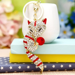 Close-up of sparkling rhinestone fox keychain with a red crystal ball and golden ring