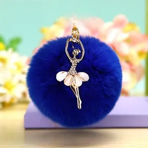 Détail d'un porte-clés pompon bleu avec une figurine de ballerine dorée et strass
