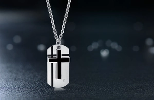 Detailed macro of a two-tone steel cross pendant with brushed finish and small inset diamond