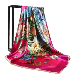 Magenta satin square silk-like scarf with vibrant floral patterns on a display stand