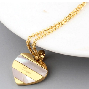 Golden heart necklace with shell inlay and Love engraving on a minimalist background