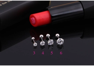 Macro view of four silver cubic zirconia stud earrings in sizes 3mm to 6mm on black mirror