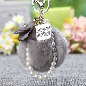 Détail du porte-clés pompon gris avec perles et plaque en argent gravée Live Well