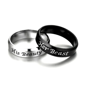 Close-up of 'His Beauty' and 'Her Beast' engraved couple rings in silver and black finish.