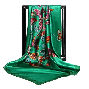 Elegant emerald green silk scarf with vibrant butterfly patterns on a minimalist black frame
