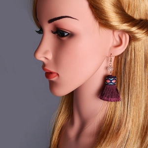 Detalle de pendientes largos bohemios con borlas de seda moradas y bordado étnico