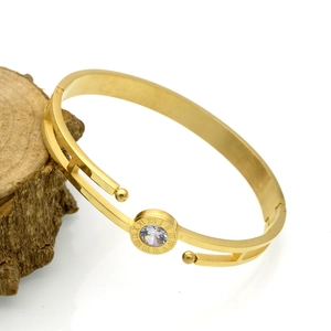 Detailed macro of golden bangle featuring Roman numeral engraving and center zircon stone