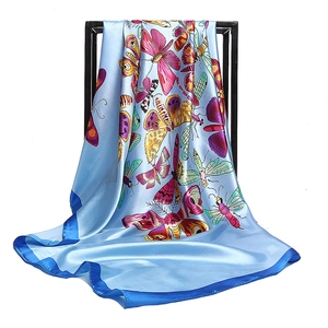 Satin silk scarf with vibrant butterfly prints hanging on a stand against white background