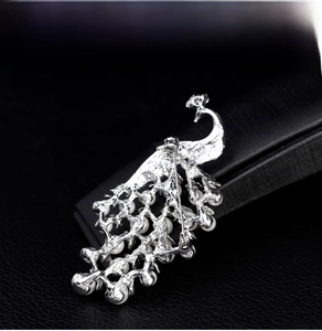Detailed close-up of peacock brooch with 18k white pearls and polished silver finish
