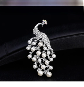 Detailed view of 18k white pearl peacock brooch with crystal rhinestones on jewelry box