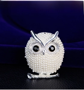 Macro shot of owl brooch with silver metal, white pearls and black gemstone eyes