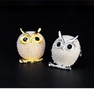 Detail shot of vintage owl brooches with white pearls and black gemstone eyes