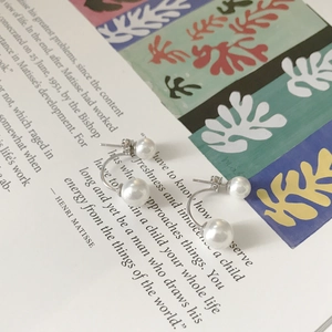 Artistic display of C-shaped 925 silver earrings with white pearls on a Matisse book