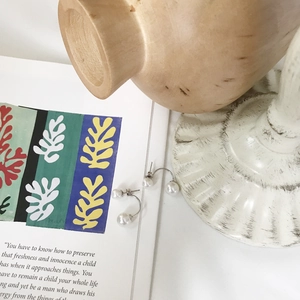Artistic detail of double-sided silver pearl earrings resting on an open book page