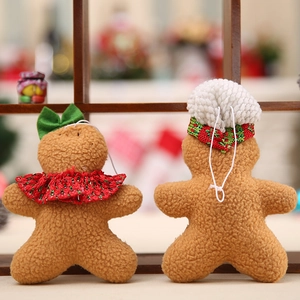 Pair of plush gingerbread man Christmas ornaments with red and green details on wood