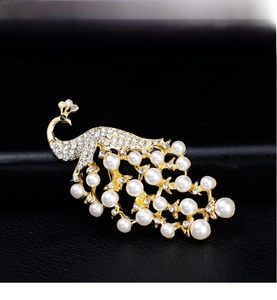 Detailed macro of a 18k gold peacock brooch with white pearls and sparkling rhinestones