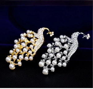 Close-up of gold and silver peacock brooches with white pearls and sparkling rhinestones