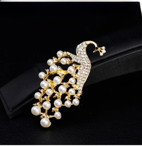 Detailed close-up of peacock brooch with white pearls and sparkling crystals on gold metal