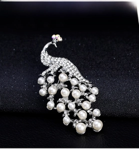Macro detail of 18k silver peacock brooch with white pearls and sparkling rhinestones