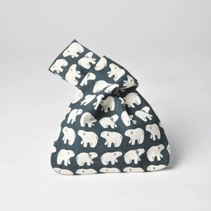 Detail of grey linen wrist bag featuring white polar bear patterns and a Japanese knot