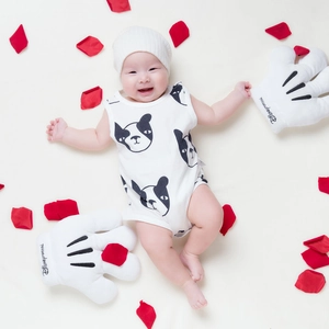 Détail d'une barboteuse bébé en coton rayé avec motif chien et bonnet en tricot blanc