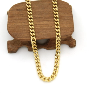 Close-up of a 3mm golden stainless steel Cuban link chain on a dark wooden stand