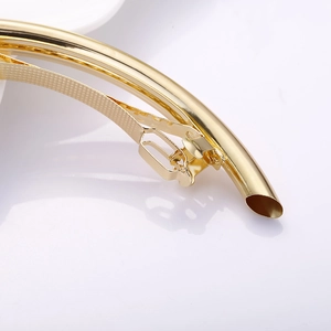 Detailed macro shot of a polished gold copper tube spring hair clip with mirror finish
