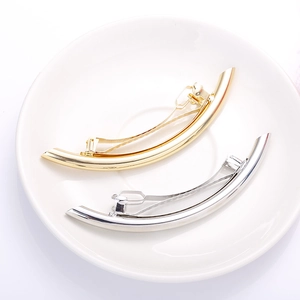 Detailed close-up of curved polished metal hair clips in gold and silver finish