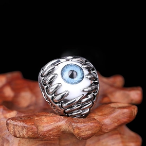 Gothic evil eye ring with blue iris and silver claws on wood texture surface