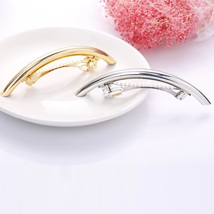 Polished metal spring hair clips in gold and silver finish on a white ceramic plate