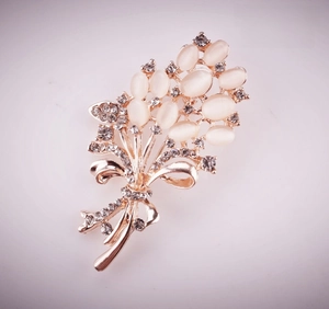 Macro detail of cat eye stone flower brooch with rhinestones and bow on rose gold stem
