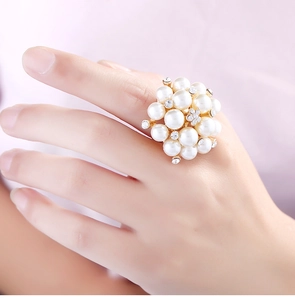 Detail of adjustable pearl ring with gold base and rhinestones worn on finger