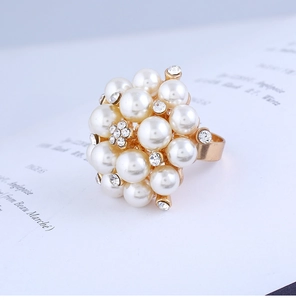 Macro detail of adjustable gold pearl ring with rhinestone floral clusters on paper