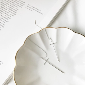 Detailed view of minimalist S925 sterling silver cross threader earrings on a white plate