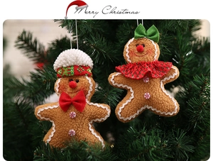 Close-up of plush gingerbread man ornaments hanging on green Christmas tree branches