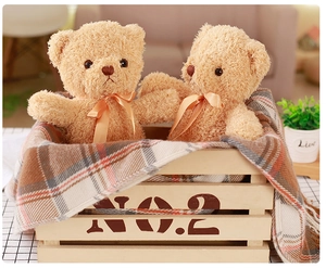 Close-up of a pair of plush teddy bears with fluffy fur and orange ribbons in a wooden box