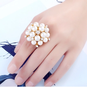 Detail of an adjustable gold ring featuring a cluster of white pearls and crystal flowers