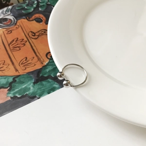 Detailed view of S925 sterling silver open ring with double beads on a white ceramic plate