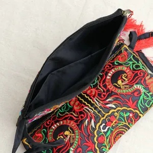 Detail of ethnic embroidered handbag with floral patterns, zipper closure and red tassel