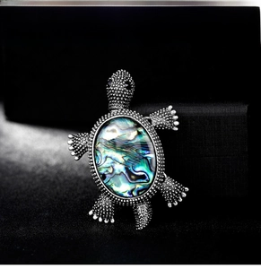 Detailed macro view of vintage silver turtle brooch featuring colorful abalone shell inlay