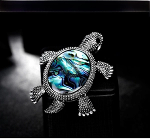 Macro detail of vintage silver turtle brooch featuring colorful iridescent abalone shell